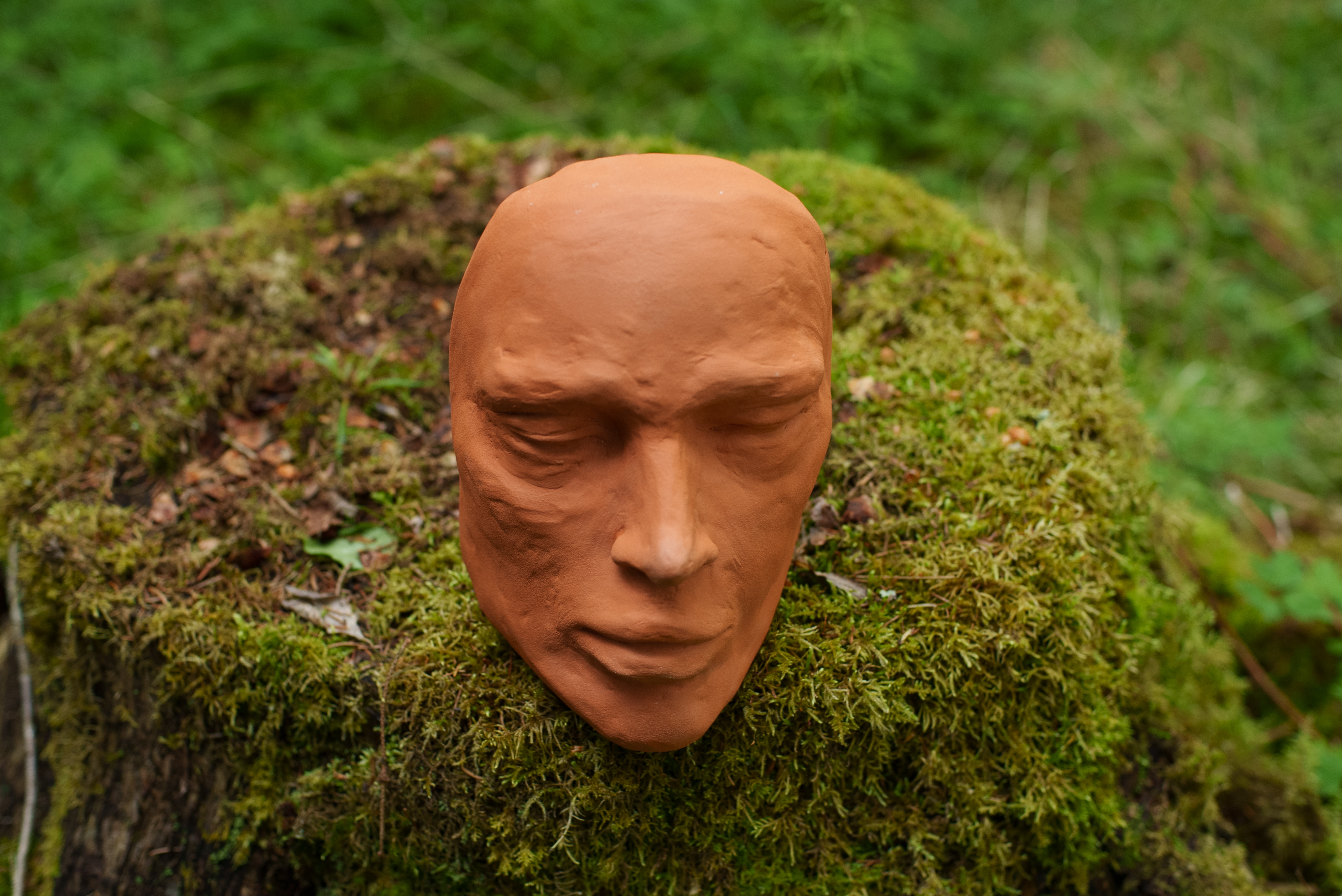 Ansikt i terracotta på mose